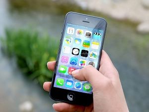 Hand holding an iPhone with app icons on screen