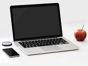 MacBook with a smartphone and an apple on a desk
